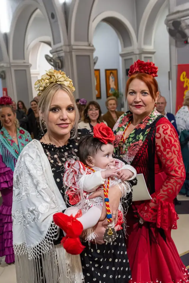 Dos hermanas con un bebé que luce la medalla de la Hermandad